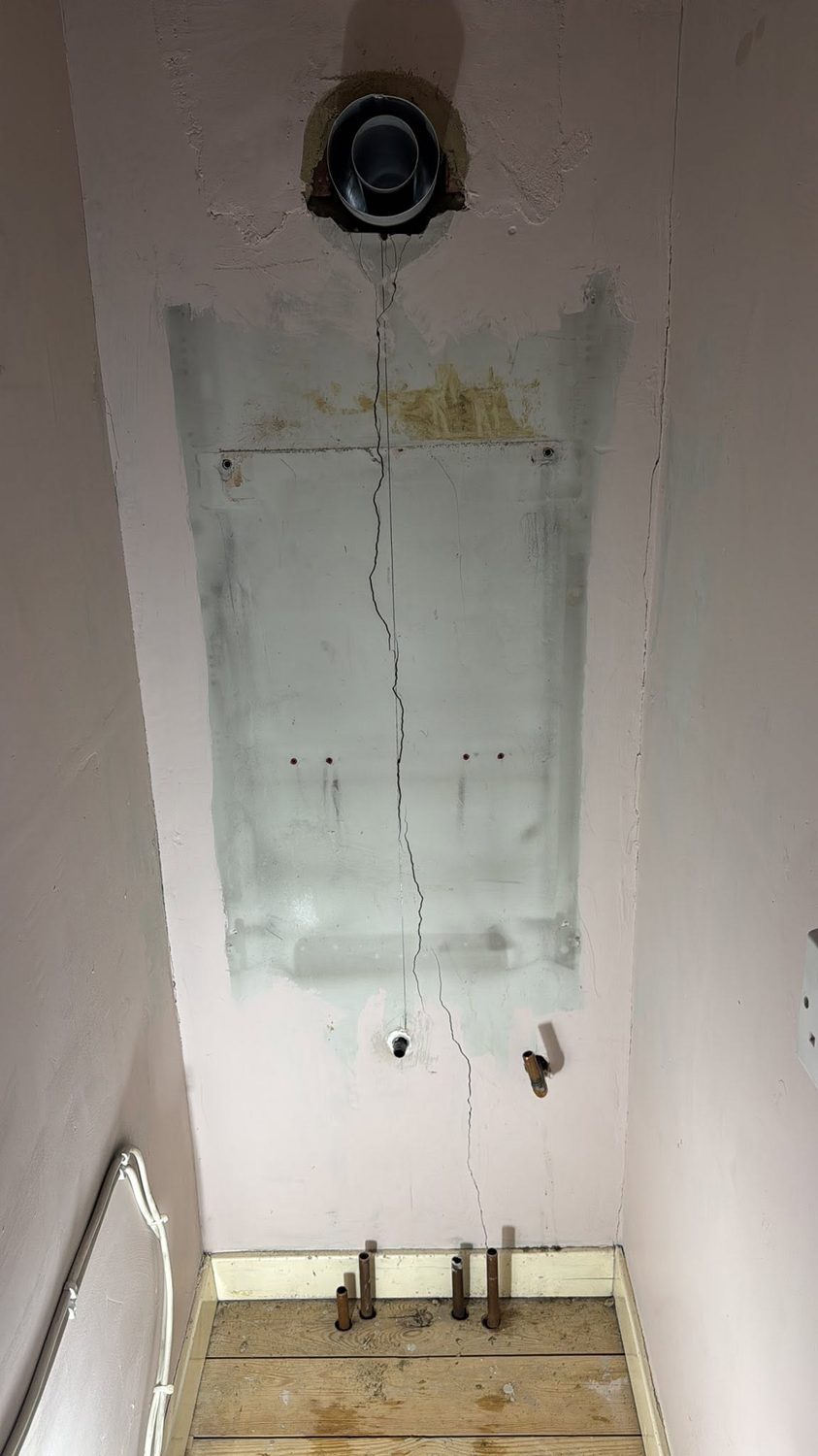 Stripped wall and old pipework before boiler install